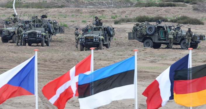 In this June 18, 2015,file photo flags wave in front of soldiers who take positions with their army vehicles during the NATO Noble Jump exercise on a training range near Swietoszow Zagan, Poland In this June 18, 2015,file photo flags wave in front of soldiers who take positions with their army vehicles during the NATO Noble Jump exercise on a training range near Swietoszow Zagan, Poland